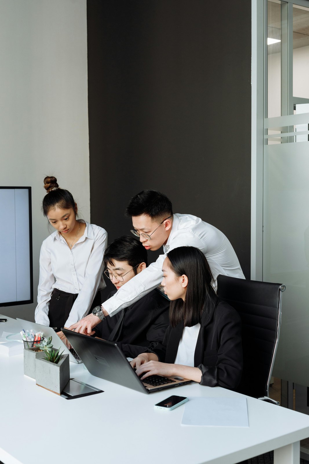 Business team reviewing operational work on laptops